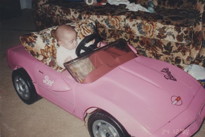Kyle in a Barbie car. He's very small. It's pink.