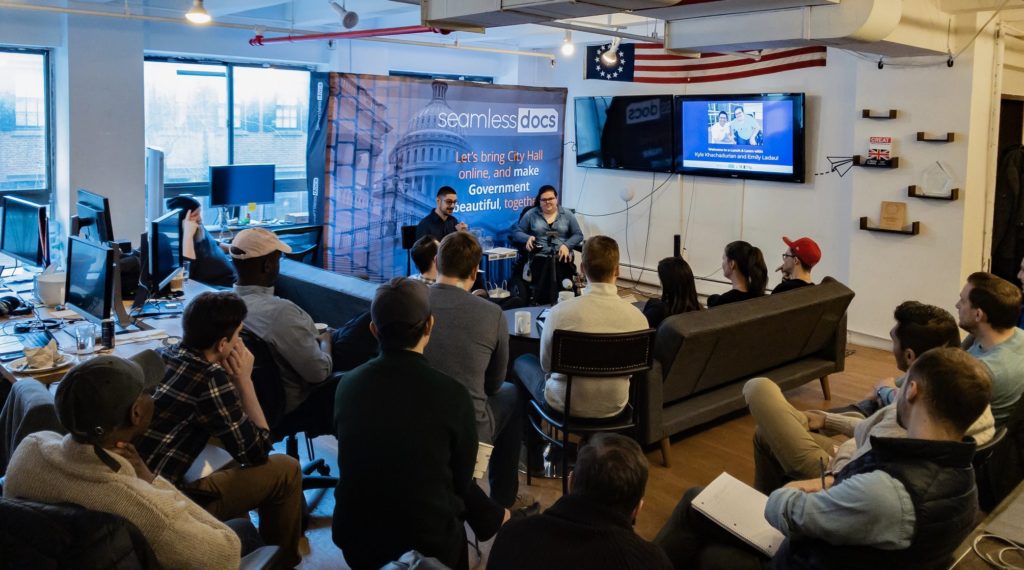 Photo of Emily and Kyle speaking in front of a group of SeamlessDocs employees